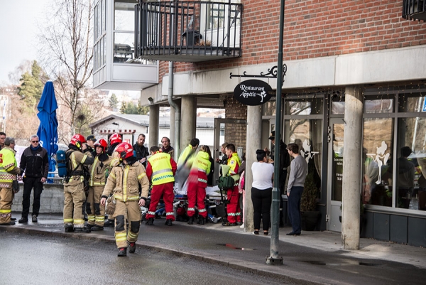 Beboerne ble evakuert til fortauet. Kvinnen som bor i leiligheten blir her fraktet bort av ambulansepersonell.