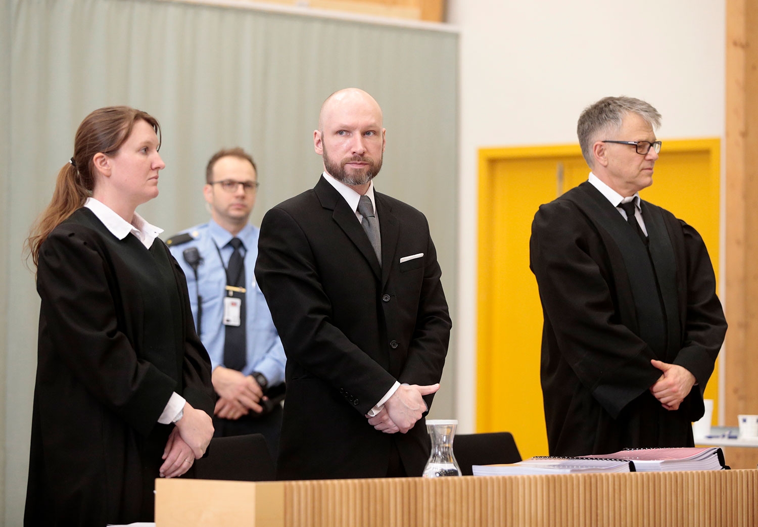 Anders Behring Breivik under behandlingen av søksmålet mot staten i 2017. Ved siden av ham står advokatene Mona Danielsen og Øystein Storrvik. 